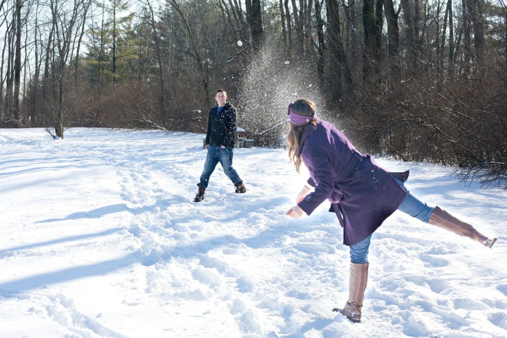 wedding couple having snowball fight before their utah winter wedding.